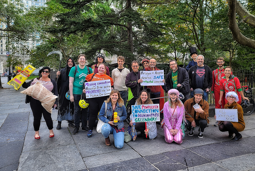 Human-bike lane participants in front of City Hall Park holding signs demanding a safe #RideToWestSide